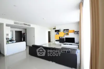 Spacious modern living room with sleek black sofa and vibrant shelving