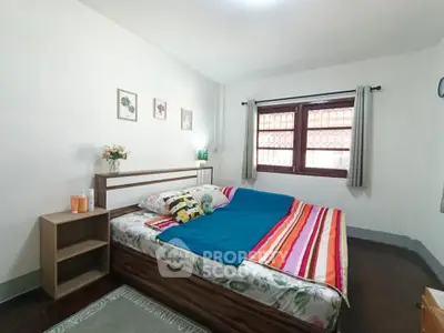Cozy bedroom with colorful bedding and natural light, perfect for relaxation.