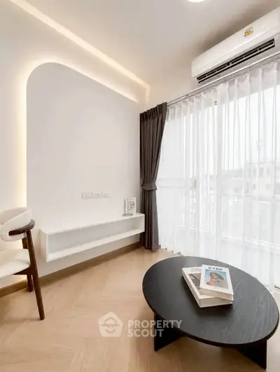 Modern living room with sleek furniture and large window offering natural light.