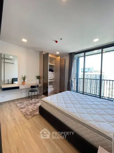 Modern bedroom with large windows and city view, featuring a cozy bed and stylish decor.