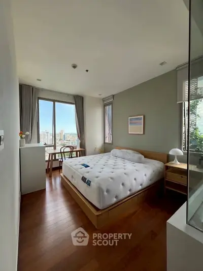 Bright and cozy bedroom with large window and city view, featuring modern decor and wooden flooring.