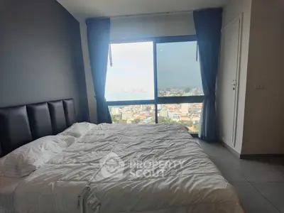 Spacious bedroom with stunning city and sea view from large window, featuring modern decor and cozy ambiance.