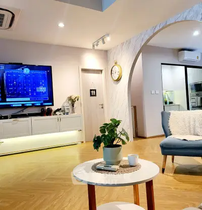 Modern living room with stylish decor and open layout, featuring a cozy seating area and wall-mounted TV.