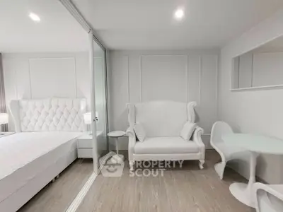 Elegant white bedroom with luxurious tufted bed and stylish seating area.