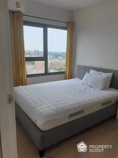 Cozy bedroom with city view and large window, featuring a comfortable bed and modern decor.