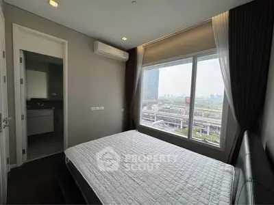 Modern bedroom with large window offering city view and sleek interior design.