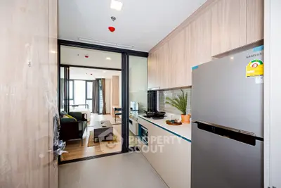 Modern kitchen with sleek appliances and open layout leading to stylish living room.