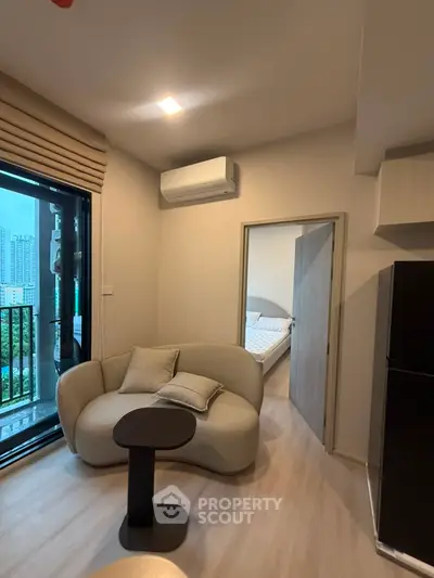 Modern living room with cozy seating and balcony view in urban apartment