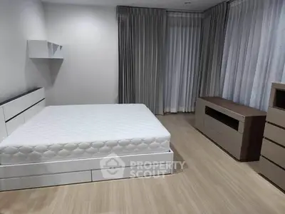 Spacious modern bedroom with minimalist design and ample natural light.