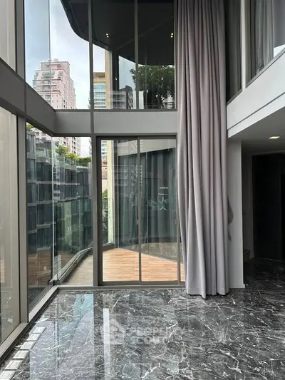 Luxurious modern apartment with floor-to-ceiling windows and marble flooring offering stunning city views.