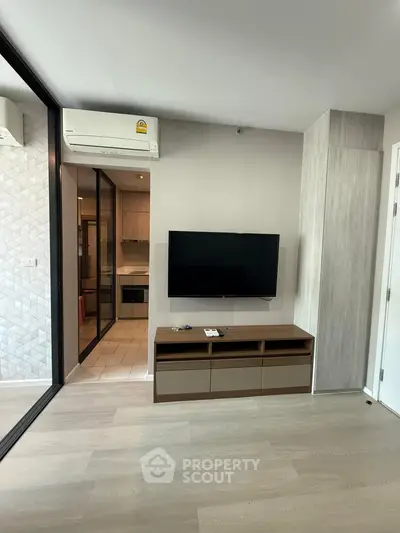 Modern living room with sleek TV setup and stylish kitchen view