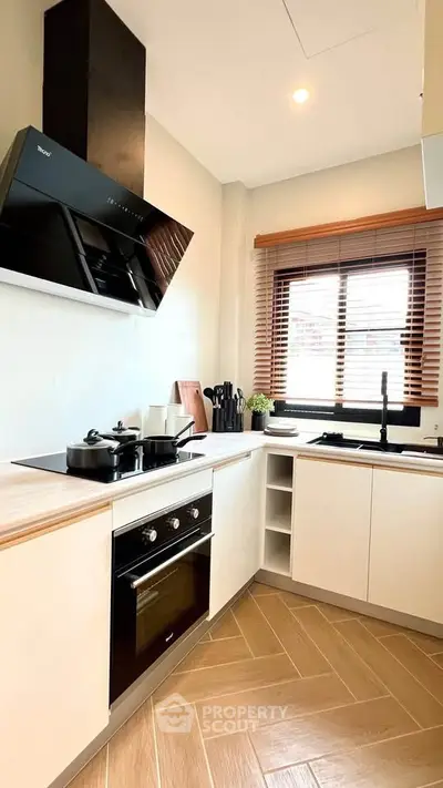Modern kitchen with sleek appliances and wooden flooring, featuring a stylish oven and ample natural light.