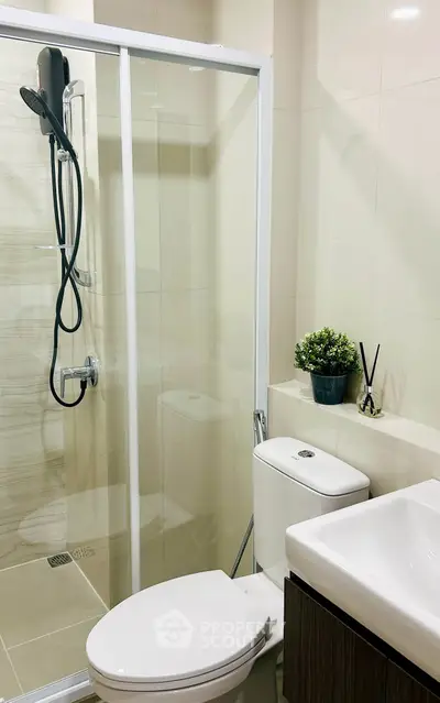 Modern bathroom with glass shower and sleek fixtures in contemporary apartment.