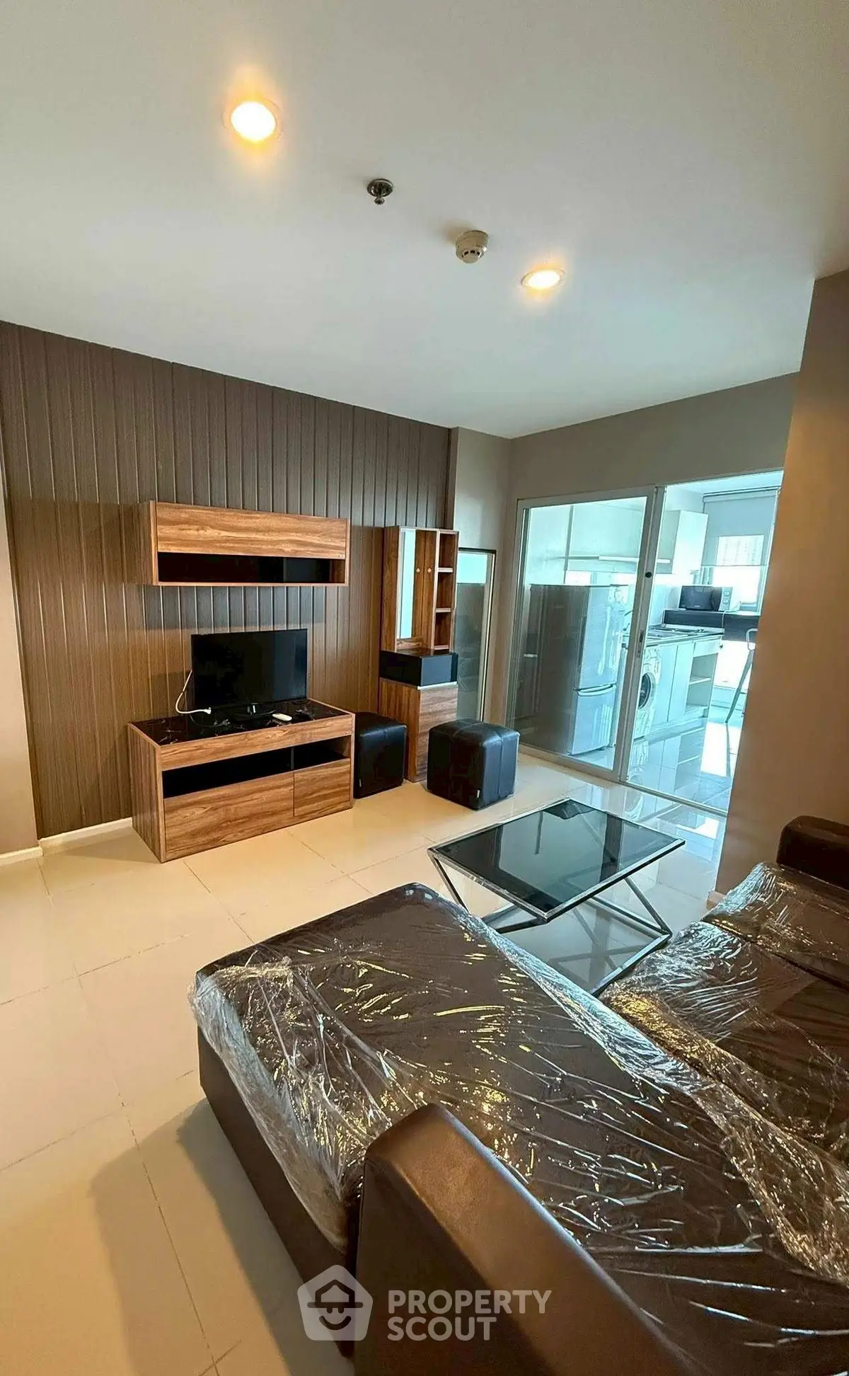 Modern living room with sleek furniture and glass coffee table, adjacent to a bright balcony area.