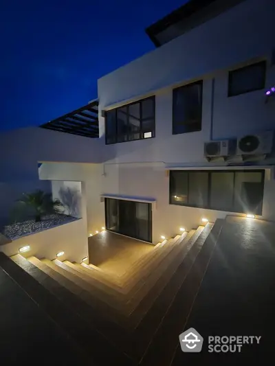 Modern architectural exterior with illuminated stairs and sleek design at dusk