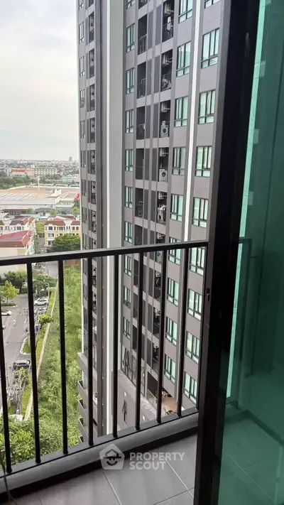 Modern high-rise apartment balcony with city view and sleek glass railing.