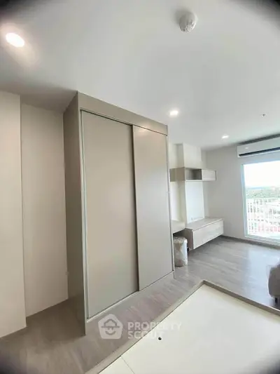 Modern bedroom with built-in wardrobe and balcony view, featuring sleek design and ample natural light.