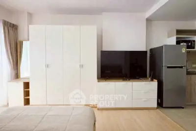 Modern bedroom with sleek wardrobe, TV unit, and stainless steel fridge in a cozy apartment.
