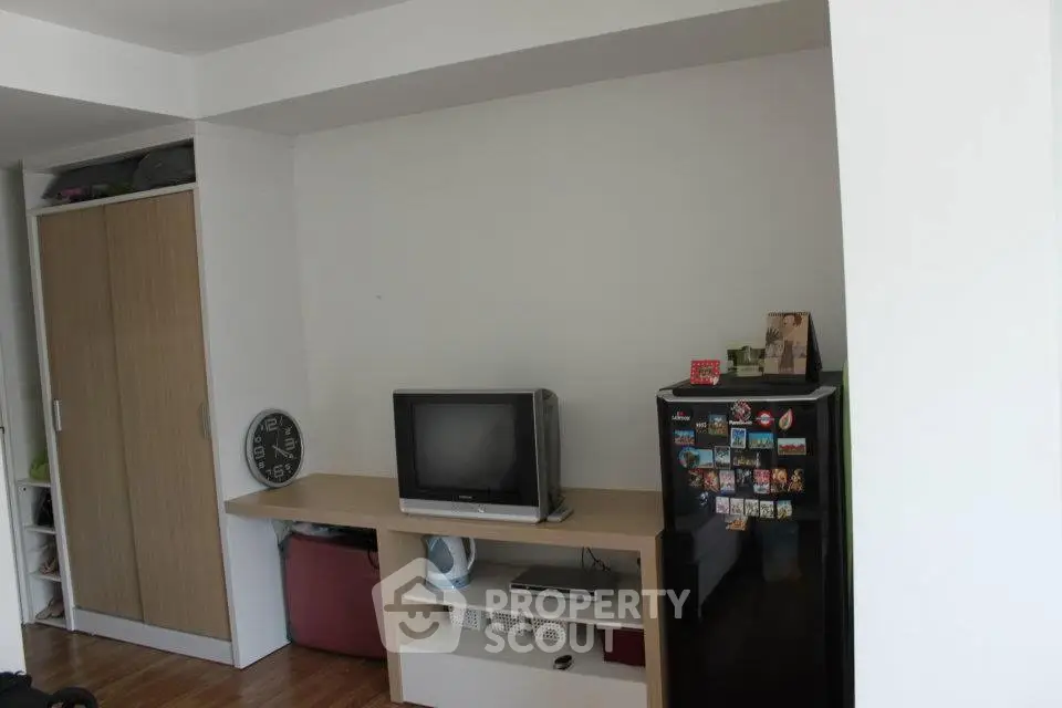 Cozy living room with TV, mini fridge, and storage space in modern apartment.