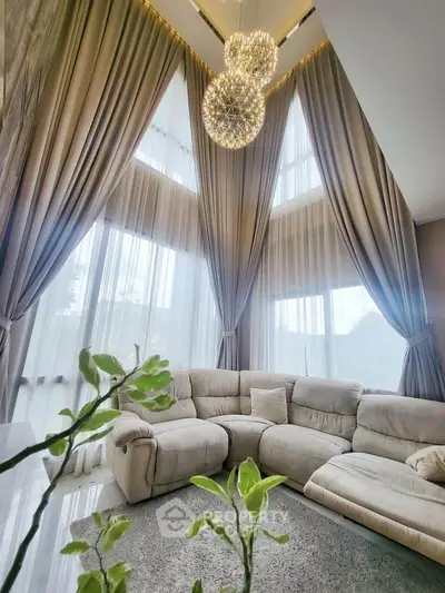 Luxurious living room with high ceilings, elegant drapes, and plush seating, perfect for sophisticated living.