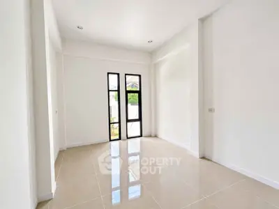 Spacious empty room with large windows and glossy tiled floor in modern home.