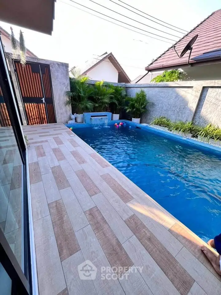 Charming backyard pool with modern tiles and lush greenery in a serene setting.