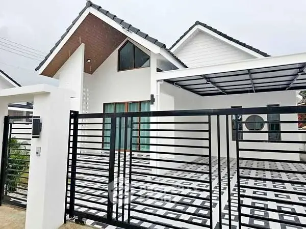Modern white house with stylish black gate and geometric driveway design.