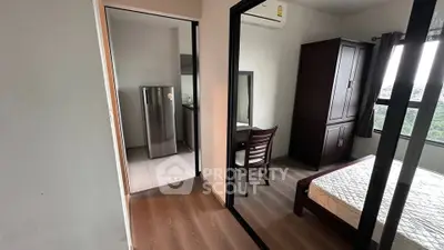 Modern apartment bedroom with wooden flooring and adjacent kitchen area.