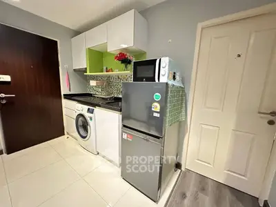 Compact kitchen with washing machine and fridge in modern apartment
