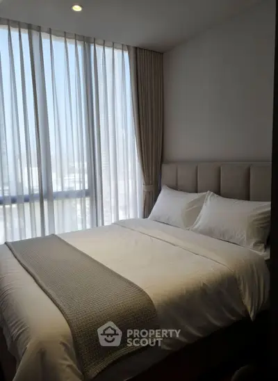 Modern bedroom with large window and elegant curtains in a high-rise apartment.
