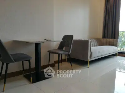 Modern living room with sleek sofa and dining set, featuring elegant decor and natural light.