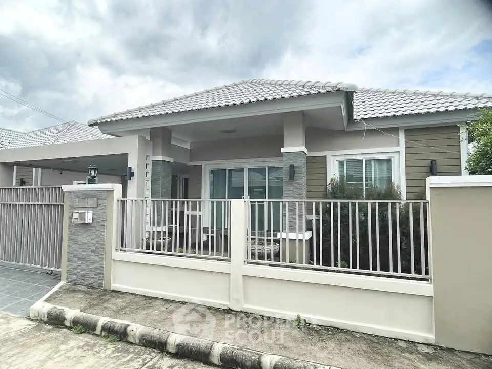 Charming single-story house with modern design and fenced yard under a cloudy sky.