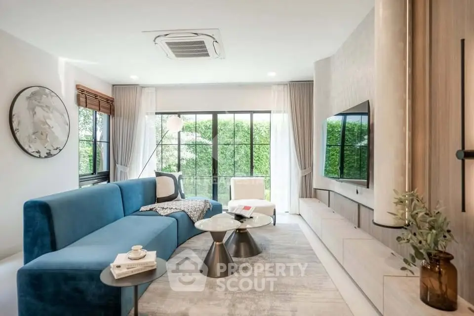 Modern living room with blue sofa, large windows, and stylish decor