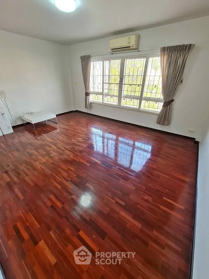 Spacious living room with polished wooden floors and large windows.