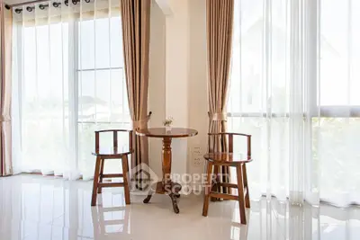 Bright and airy corner with elegant wooden chairs and table, surrounded by floor-to-ceiling windows and curtains.