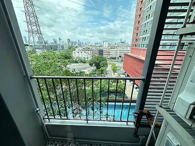 Stunning urban view from a high-rise balcony overlooking a pool and city skyline.