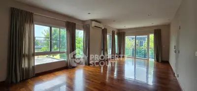 Spacious living room with large windows and polished wooden floors