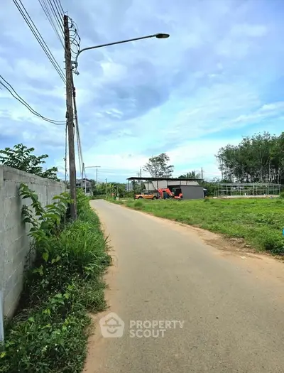 Scenic rural road with lush greenery and open sky, perfect for peaceful living.