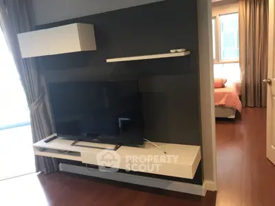 Modern living room with sleek TV setup and view into cozy bedroom
