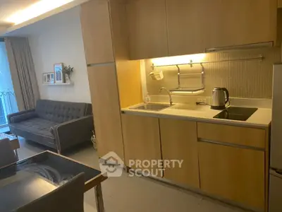 Modern kitchen with wooden cabinets and cozy living area in open layout apartment.