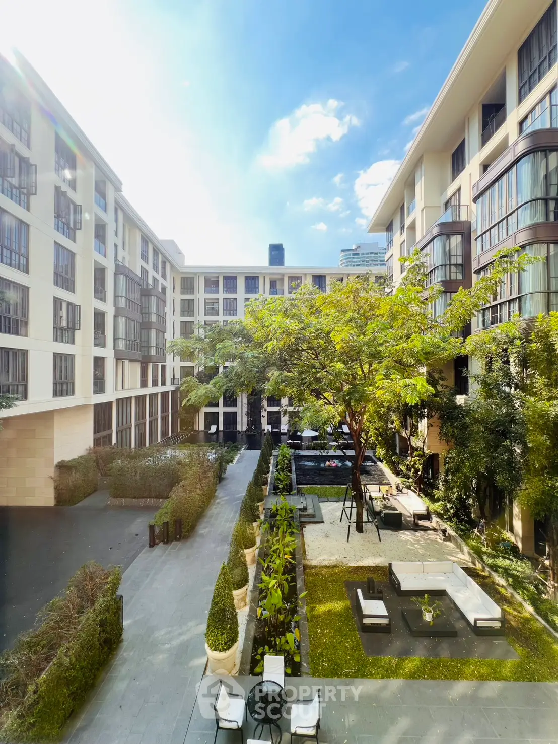 Luxurious modern apartment complex with lush courtyard and outdoor seating area.