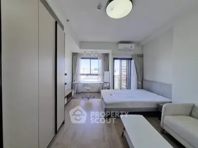 Modern bedroom with city view, featuring a cozy bed, study area, and sleek furnishings.