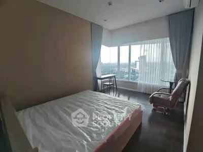 Spacious bedroom with large windows offering a stunning city view.