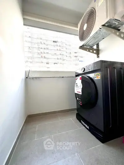 Compact laundry area with modern washing machine and air conditioning unit.