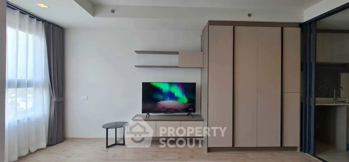 Modern living room with sleek TV setup and large window for natural light.