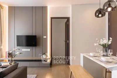 Modern living room with stylish decor and open dining area, featuring elegant lighting and contemporary furniture.