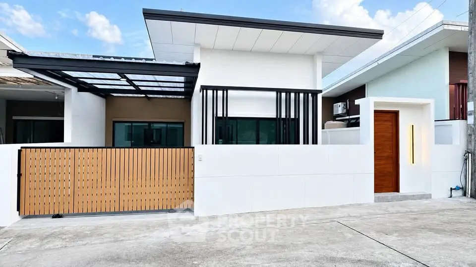 Modern single-story house with sleek design and wooden accents, featuring a gated entrance and contemporary facade.