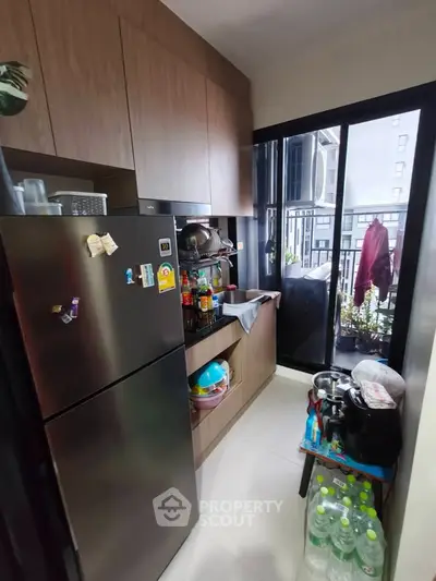 Compact kitchen with modern appliances and balcony view in urban apartment.