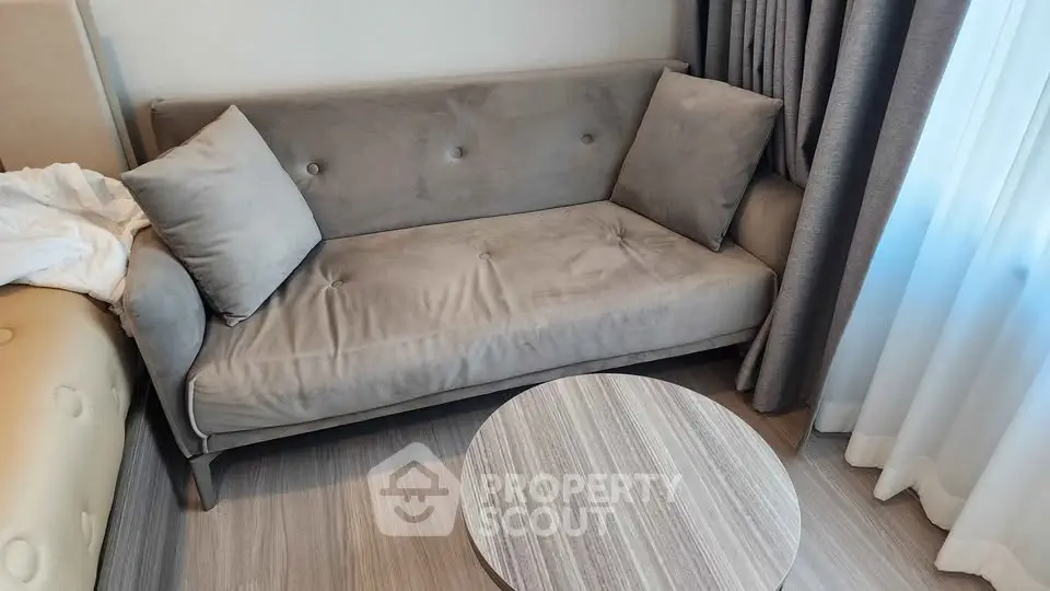 Cozy living room with stylish gray sofa and round wooden coffee table, perfect for relaxation.