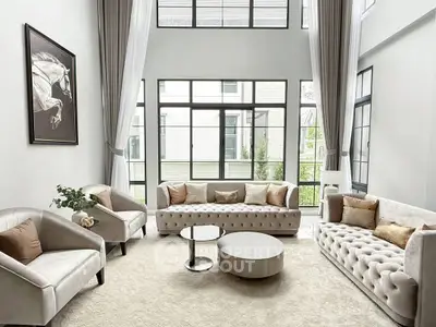 Luxurious living room with high ceilings, elegant sofas, and large windows offering abundant natural light.
